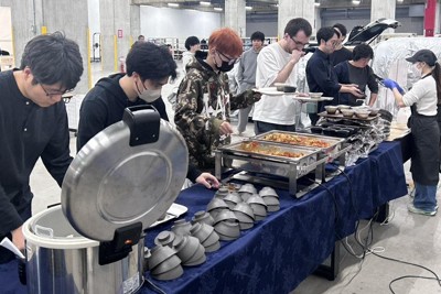 ランチタイムになり、行列を作るTuringの社員たち。本来は倉庫兼作業場のため、システム開発用の車も後方に並ぶ＝東京都大田区で2026年3月27日午後0時17分、森田采花撮影