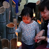 火がともされた竹灯籠を見つめる子ども＝熊本県益城町で2026年4月14日午後6時50分、金澤稔撮影