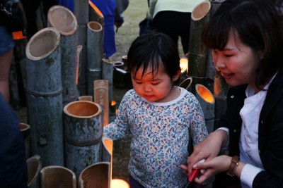 火がともされた竹灯籠を見つめる子ども＝熊本県益城町で2026年4月14日午後6時50分、金澤稔撮影