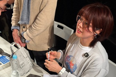 映画のプログラムにサインする松本麗華さん＝東京都渋谷区で5日