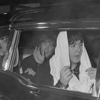 公演を終え、車でホテルに向かうビートルズの（右から）タオルをかぶったポール・マッカートニー、手を振るジョン・レノン、リンゴ・スター＝東京都千代田区で1966年6月30日、出版写真部員撮影