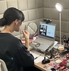 This photo provided by Shiseido Co. shows a beauty consultant providing advice via sign language to a client on the other side of a computer screen, in Tokyo's Minato Ward.