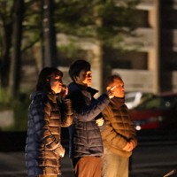 亡くなった大和晃さんに黙とうし、旧阿蘇大橋の方向を指さす兄の翔吾さん（中央）と母の忍さん（左）＝熊本県南阿蘇村で2026年4月16日午前1時半、金澤稔撮影
