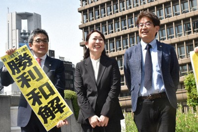 海外出向中に過労自殺したとして遺族が川崎重工業を訴えていた訴訟で和解が成立し、「勝利和解」の旗を掲げる代理人弁護士と、亡くなった清島浩司さんの妻・験馬綾子さん（中央）＝大阪市内で2026年4月17日午後1時45分、岩崎歩撮影