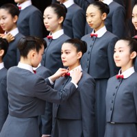 宝塚音楽学校の入学式前の記念撮影で、本科生に制服を整えてもらう新入生＝兵庫県宝塚市で2026年4月18日午前9時11分、前田梨里子撮影