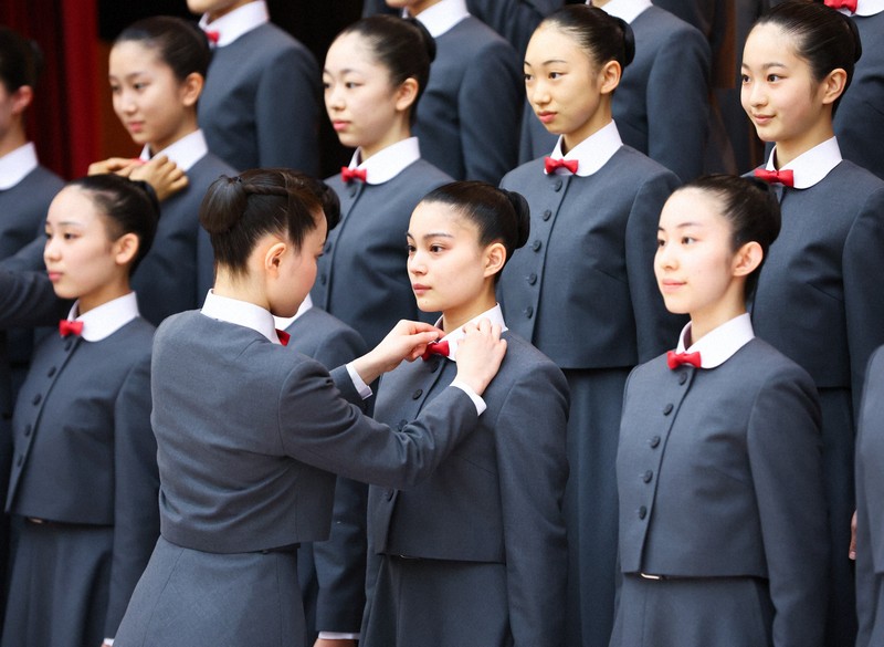 宝塚音楽学校の入学式前の記念撮影で、本科生に制服を整えてもらう新入生＝兵庫県宝塚市で2026年4月18日午前9時11分、前田梨里子撮影
