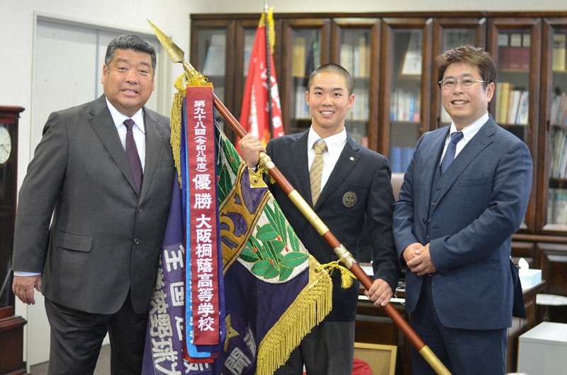 ペナントを取り付けたセンバツ優勝旗を囲む大阪桐蔭の平井了校長（右）と黒川虎雅主将（中央）、西谷浩一監督＝大東市の同校で2026年4月20日午前10時9分、藤河匠撮影
