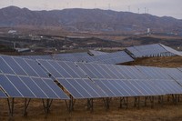 A solar farm operates with wind turbines in the background in Datong, China, March 13, 2026. (AP Photo/Ng Han Guan)