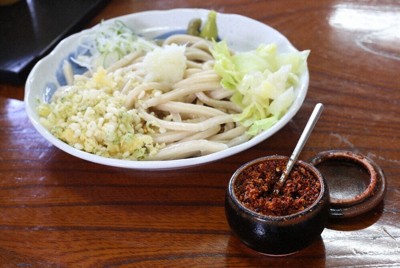 吉田のうどん（左奥）と薬味のすりだね。店の卓上に必ず置かれている＝山梨県富士吉田市松山4の「吉田うどん　ふじや」で
