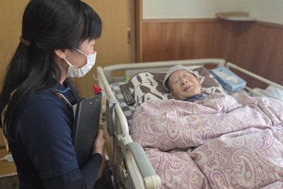 梅田みつよさん（左）の訪問を受け、穏やかな表情を浮かべる男性。末期がんだったが、状態に見合う要介護認定が間に合わないまま、3月初旬に亡くなった＝岐阜県白川町で1月29日、宇多川はるか撮影