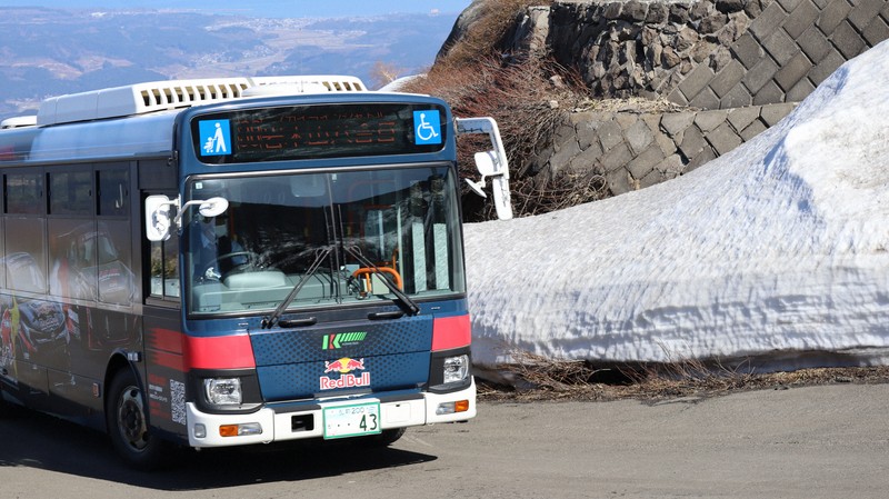 雪の回廊を通って岩木山8合目に向かうバス＝青森県弘前市の岩木スカイラインで2026年4月23日午前8時52分、山越峰一郎撮影