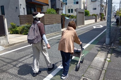 脊椎（せきつい）圧迫骨折で歩行器を頼りに外出する女性（右）。家族が付き添うこともしばしばという＝東京都内で2026年4月18日午前11時、田中泰義撮影