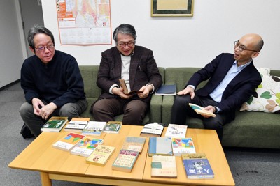 D・カーネギー著『人を動かす』のさまざまな版と関連書を前に語り合う三砂慶明さん（右）と創元社の担当者、松浦利彦さん（左）、矢部敬一社長＝大阪市中央区で2026年2月27日、加古信志撮影