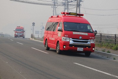 山林火災による煙が立ちこめる中消火作業に向かう消防車両＝岩手県大槌町で2026年4月24日午後2時31分、奥田伸一撮影