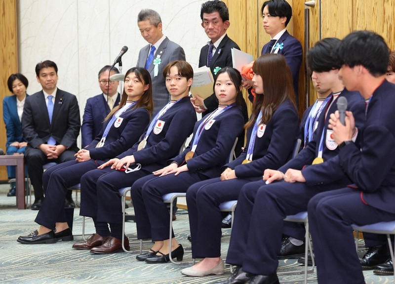 首相表敬訪問で視界を遮らないようのけぞる（中央左から）坂本花織さん、鍵山優真さん、中井亜美さん＝首相官邸で2026年4月24日午後6時27分、猪飼健史撮影