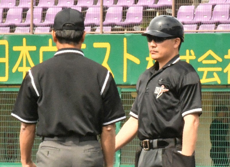 社会人野球のJABA京都大会で、ヘルメットをかぶって臨む球審（右）。塁審は従来通り帽子を着用している＝京都市右京区のわかさスタジアム京都で2026年4月25日午前9時13分、石川裕士撮影
