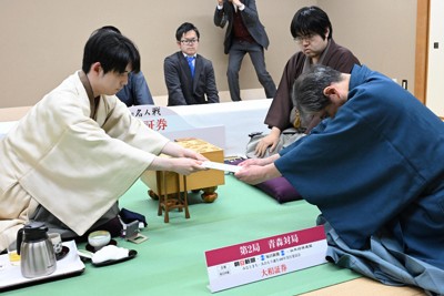 第84期名人戦七番勝負第2局で、立会の行方尚史八段（右手前）に封じ手を渡す藤井聡太名人（左）。右奥は挑戦者の糸谷哲郎九段＝青森市のホテル青森で2026年4月25日、平川義之撮影