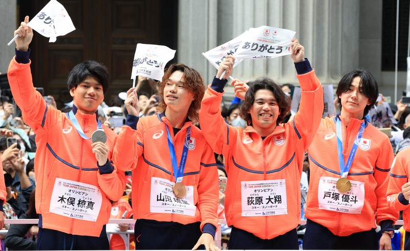 ミラノ・コルティナ冬季オリンピック・パラリンピック日本選手団の応援感謝イベントで、日本橋の街を練り歩き観客の声援に答える（左から）スノーボード男子ビッグエア・スロープスタイルの木俣椋真さん、ハーフパイプの山田琉聖さん、ビッグエア・スロープスタイルの荻原大翔さん、ハーフパイプの戸塚優斗さん＝東京都中央区で2026年4月25日午前9時47分、滝川大貴撮影