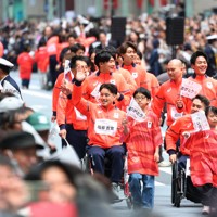 日本橋をパレードするパラアイスホッケーの塩谷吉寛さん（手前左端）らミラノ・コルティナオリンピック、パラリンピックの日本代表選手たち＝東京都中央区で2026年4月25日午前9時56分、猪飼健史撮影