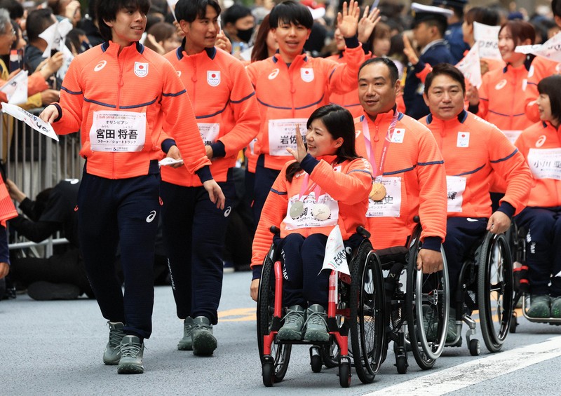 ミラノ・コルティナ冬季オリンピック・パラリンピック日本選手団の応援感謝イベントで、日本橋の街を練り歩き観客の声援に応えるパラアルペンスキーの（右列手前から）村岡桃佳さん、鈴木猛史さんら選手たち＝東京都中央区で2026年4月25日午前9時40分、滝川大貴撮影