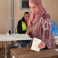 投票用紙を投票箱に入れる女性＝パレスチナ自治区ガザ地区中部デルバラーで2026年4月25日、アナス・カフルート撮影