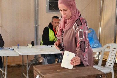 投票用紙を投票箱に入れる女性＝パレスチナ自治区ガザ地区中部デルバラーで2026年4月25日、アナス・カフルート撮影