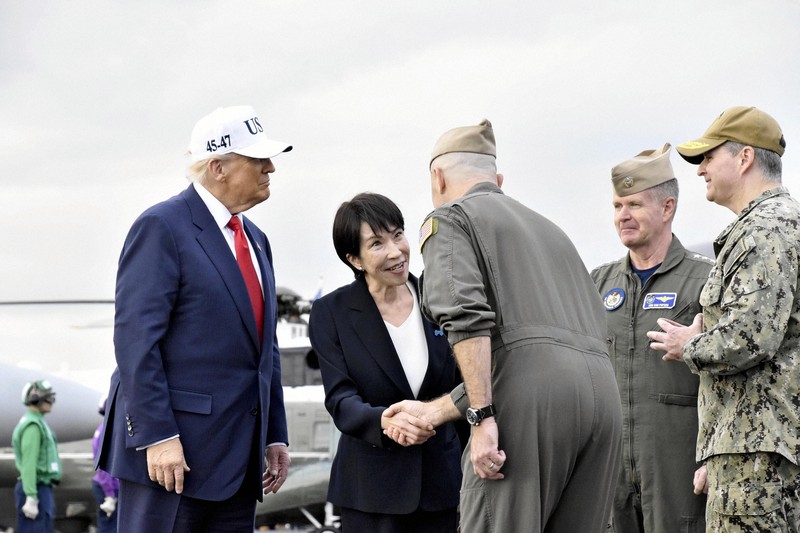 米海軍横須賀基地に停泊中の米原子力空母「ジョージ・ワシントン」に到着し、米軍関係者から歓迎を受ける高市早苗首相（中央）とトランプ米大統領（左）＝神奈川県横須賀市で2025年10月28日午後3時53分（代表撮影）
