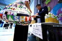 A participant, holding merchandise from an idol group concert, registers for a nighttime stay event using limited express train cars, as hotel prices surged due to overlapping events in Fukuoka, in this photo taken in the city's Hakata Ward, April 25, 2026. (Mainichi/Tatsuro Tamaki)