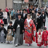 花嫁道中で商店街の通りをゆっくりと歩く比留間希星さん（中央左）とサヴェンコ・ヴァレリヤさん（同右）＝石川県七尾市で2026年4月29日午前9時23分、岩本一希撮影