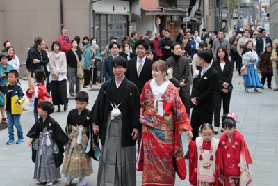 花嫁道中で商店街の通りをゆっくりと歩く比留間希星さん（中央左）とサヴェンコ・ヴァレリヤさん（同右）＝石川県七尾市で2026年4月29日午前9時23分、岩本一希撮影