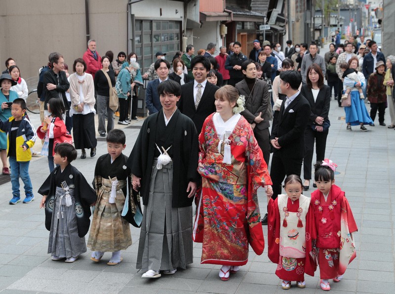 花嫁道中で商店街の通りをゆっくりと歩く比留間希星さん（中央左）とサヴェンコ・ヴァレリヤさん（同右）＝石川県七尾市で2026年4月29日午前9時23分、岩本一希撮影