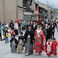花嫁道中で商店街の通りをゆっくりと歩く比留間希星さん（中央左）とサヴェンコ・ヴァレリヤ（同右）さん＝石川県七尾市で2026年4月29日午前9時23分、岩本一希撮影