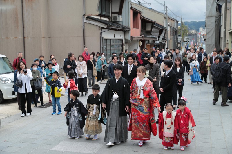 花嫁道中で商店街の通りをゆっくりと歩く比留間希星さん（中央左）とサヴェンコ・ヴァレリヤ（同右）さん＝石川県七尾市で2026年4月29日午前9時23分、岩本一希撮影