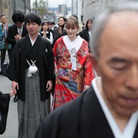 先導役に導かれながら花嫁道中で商店街の通りをゆっくりと歩く比留間希星さん（中央左）とサヴェンコ・ヴァレリヤ（同右）さん＝石川県七尾市で2026年4月29日午前9時10分、岩本一希撮影