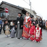地域住民に見守られながら花嫁道中で商店街の通りをゆっくりと歩く比留間希星さん（中央左）とサヴェンコ・ヴァレリヤ（同右）さん＝石川県七尾市で2026年4月29日午前9時15分、岩本一希撮影