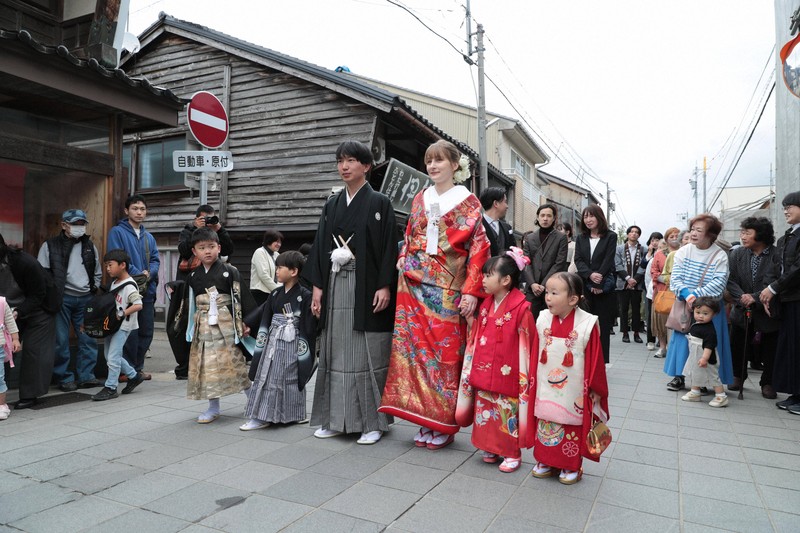 地域住民に見守られながら花嫁道中で商店街の通りをゆっくりと歩く比留間希星さん（中央左）とサヴェンコ・ヴァレリヤ（同右）さん＝石川県七尾市で2026年4月29日午前9時15分、岩本一希撮影