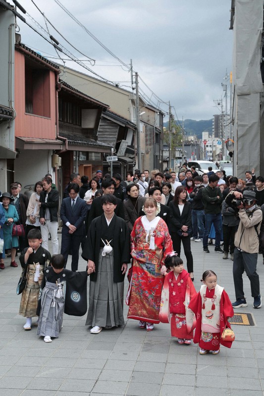 花嫁道中で商店街の通りをゆっくりと歩く比留間希星さん（中央左）とサヴェンコ・ヴァレリヤ（同右）さん＝石川県七尾市で2026年4月29日午前9時20分、岩本一希撮影