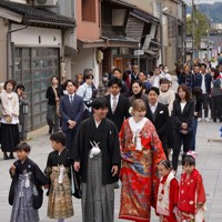 花嫁道中で商店街の通りをゆっくりと歩く比留間希星さん（中央左）とサヴェンコ・ヴァレリヤ（同右）さん＝石川県七尾市で2026年4月29日午前9時22分、岩本一希撮影