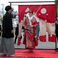 花嫁道中の最後、比留間希星さん（左）に見守られながら花嫁のれんをくぐるサヴェンコ・ヴァレリヤさん＝石川県七尾市で2026年4月29日午前9時38分、岩本一希撮影