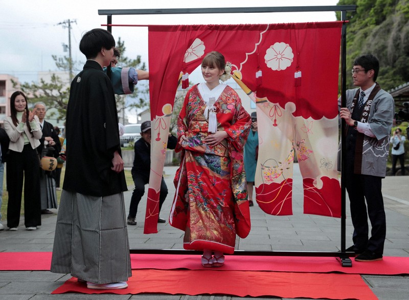 花嫁道中の最後、比留間希星さん（左）に見守られながら花嫁のれんをくぐるサヴェンコ・ヴァレリヤさん＝石川県七尾市で2026年4月29日午前9時38分、岩本一希撮影