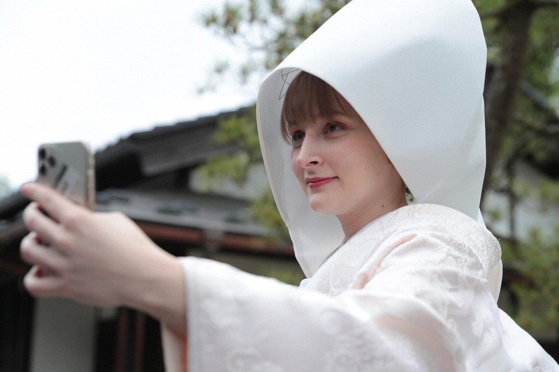 花嫁道中を終え、白むくに着替えたサヴェンコ・ヴァレリヤさんはウクライナにいる父親のオレクサンドルさんとビデオ通話をして花嫁姿を見せた＝石川県七尾市で2026年4月29日午前10時59分、岩本一希撮影