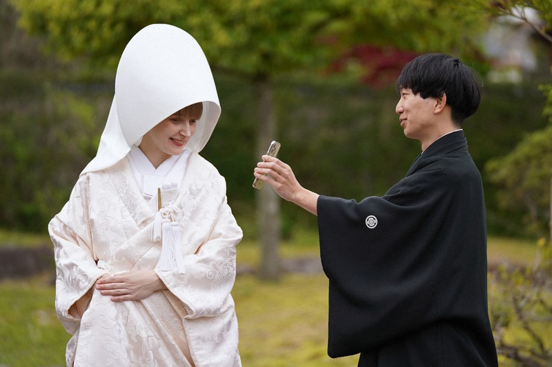 花嫁道中を終え、白むくに着替えたサヴェンコ・ヴァレリヤさん（左）は比留間希星さん（左）と一緒にウクライナにいる父親のオレクサンドルさんとビデオ通話をして花嫁姿を見せた＝石川県七尾市で2026年4月29日午前10時56分、岩本一希撮影