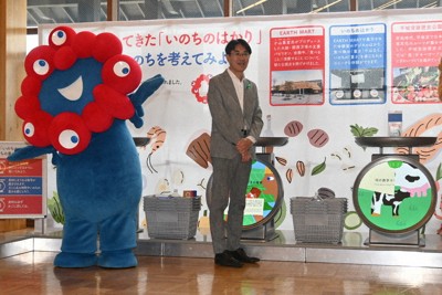 「いのちのはかり」に牛乳の模型を載せる山下真知事（右）とミャクミャク＝奈良市の平城宮跡歴史公園で、田辺泰裕撮影