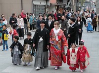 Groom Tokiya Hiruma, center left, and bride Savenko Valeriia, center right, are gently led by local children as they slowly parade along a shopping street in Nanao, Ishikawa Prefecture, April 29, 2026. (Mainichi/Kazuki Iwamoto)