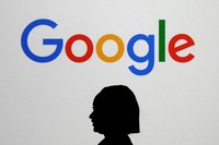 A woman walks by a giant screen displaying the Google logo at an event at the Paris Google Lab on the sidelines of the AI Action Summit in Paris, Feb. 9, 2025. (AP Photo/Thibault Camus, File)