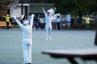 People perform a stretching exercise while listening to music and guidance from radio at a public park in Tokyo, on April 6, 2026. (AP Photo/Hiro Komae)