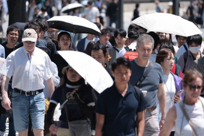 日差しが照りつける中、日傘を差して東京駅前を歩く人たち＝東京都千代田区で2026年5月2日午後0時10分、中川祐一撮影
