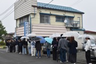 小雨の降るなか傘をさして行列に並ぶドラマのファンら＝山梨県富士吉田市で2026年4月30日正午、杉本修作撮影