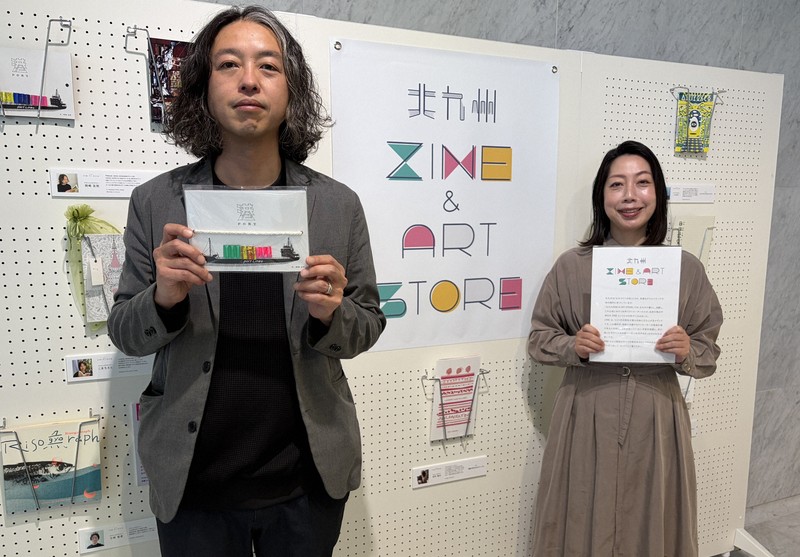 自作のZINEを手にPRする岡崎友則さん（左）と運営を担う福岡佐知子社長＝北九州市戸畑区で2026年4月29日午前10時6分、橋本勝利撮影