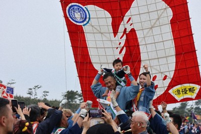 右下に子どもの名前が入った「初凧」を背に町会の人たちから祝福を受ける夫妻＝浜松市中央区で2026年5月3日午前、照山哲史撮影